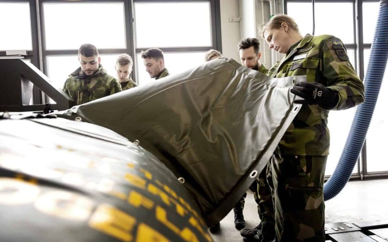 Specialistofficerskadetter övar på att täcka en vatten­tank med isoleringstäcke i en av hallarna vid Försvarsmaktens logistik- och motorskola.