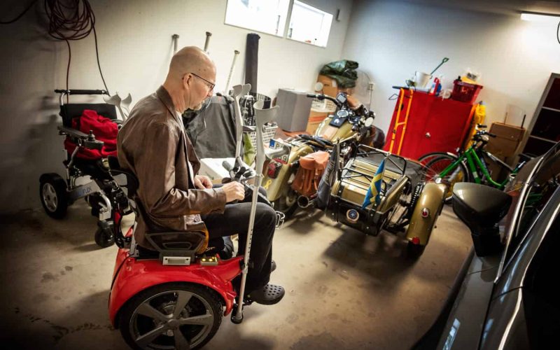 Den guldfärgade motorcykeln som står uppställd i garaget har kompletterats med sidovagn för att han ska kunna  fortsätta köra.